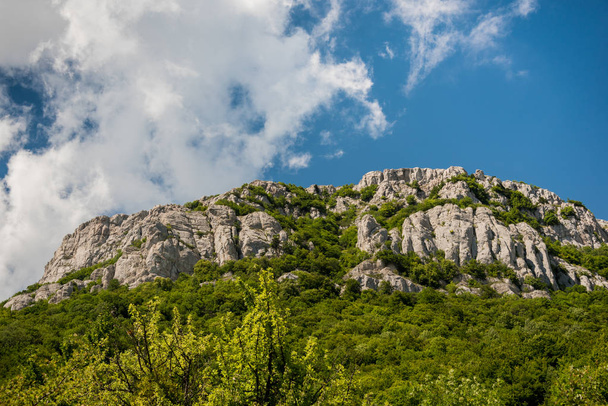Bright blue sky with white clouds over rough mountain ridge covered with green plants on sunny day - Foto, immagini