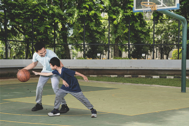 Picture of little boy and his father playing basketball while exercising in the field  - Zdjęcie, obraz