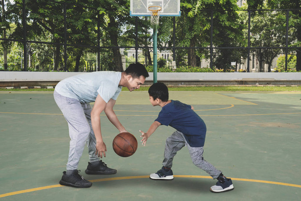 Picture of a young man and his son exercising with basketball in the field - Foto, Imagem