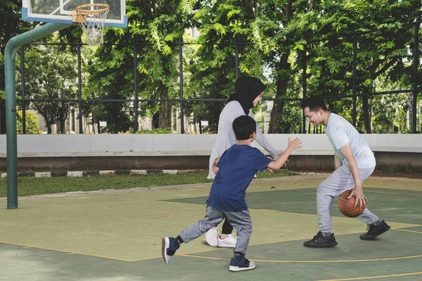 Picture of young Muslim family playing basketball while having fun in the field - Foto, Imagem