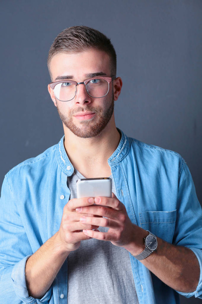Smiling young man holding phone while text messaging - Φωτογραφία, εικόνα