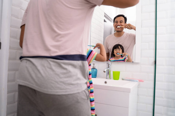 dad and girl brush their teeth together - Zdjęcie, obraz