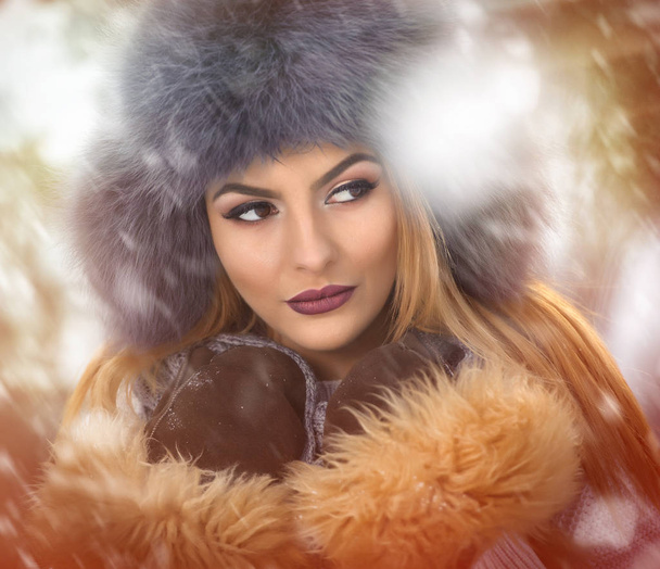Kahverengi Kürk kap ve ceket kış zevk çekici kadın. Kar kaplı köprü karşı poz moda sarışın kız yan görünüm. Güzel genç kadın, soğuk hava kıyafeti - Fotoğraf, Görsel