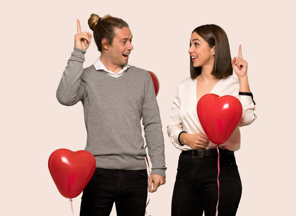 Couple in valentine day intending to realizes the solution while lifting a finger up over isolated background - Photo, Image
