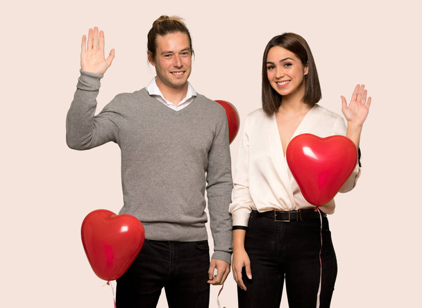 Couple in valentine day saluting with hand with happy expression over isolated background - Photo, Image