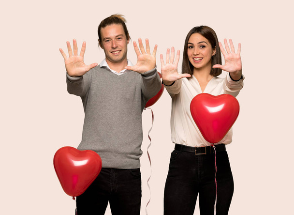 Paar am Valentinstag, das mit den Fingern vor isoliertem Hintergrund zehn zählt - Foto, Bild
