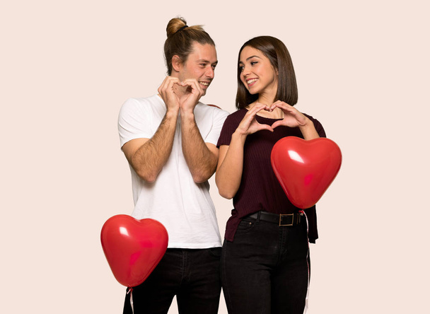 Couple in valentine day making heart symbol by hands over isolated background - Photo, Image