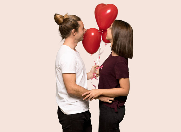 Couple in valentine day with balloons with heart shape over isolated background - Fotografie, Obrázek