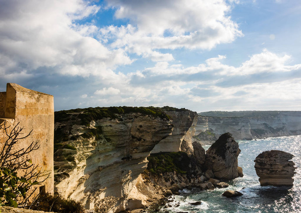 Panoramatický pohled thr skalnaté pobřeží s jasné, transparentní modrá voda, skály, obrovské kameny, trávy. Bonifacio, Korsika, Francie. - Fotografie, Obrázek
