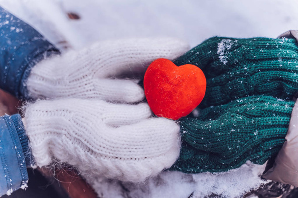 Hands in gloves holding heart closeup on winter snow background. Toned. - Фото, изображение