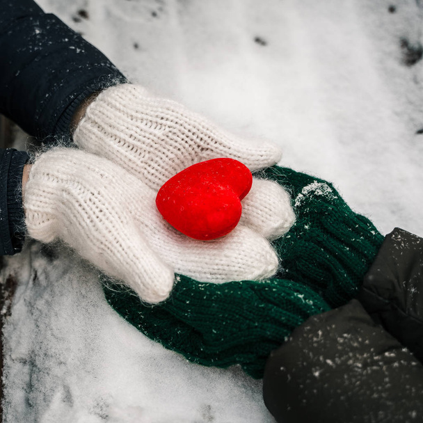 Hands in gloves holding heart closeup on winter snow background. Toned. - Фото, изображение