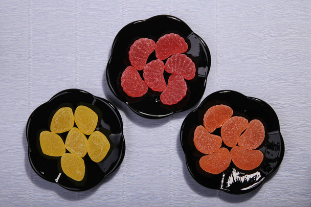Plates with sweets. Marmalade on the dish. Black dishes. Marmalade slices. - Photo, Image