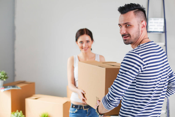 Happy young couple unpacking or packing boxes and moving into a new home. young couple - Photo, Image