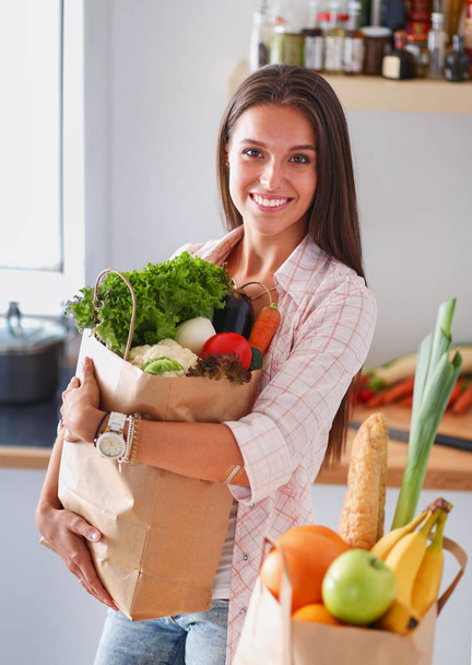 Young woman holding grocery shopping bag with vegetables. Young woman - Fotó, kép