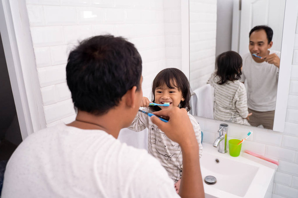 father and daughter brushing teeth together - Fotó, kép