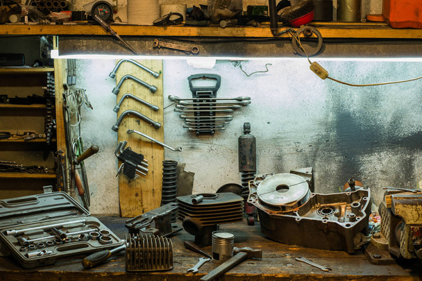 Motorfiets onderdelen en gereedschappen op het bureaublad in de garage - Foto, afbeelding
