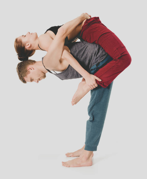 Young athletic couple practicing acroyoga. Balancing in pair. - Foto, Imagen