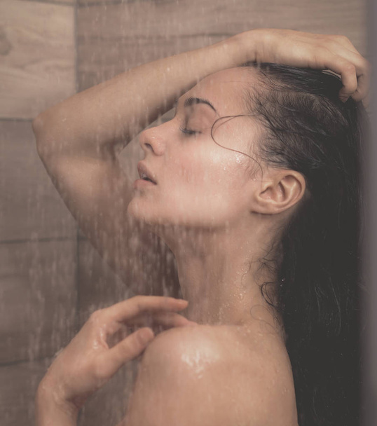 Young beautyful woman under shower in bathroom. - Foto, immagini