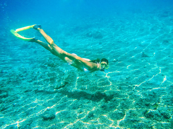 Young woman diving with snorkel in clear water near tropical island - Zdjęcie, obraz