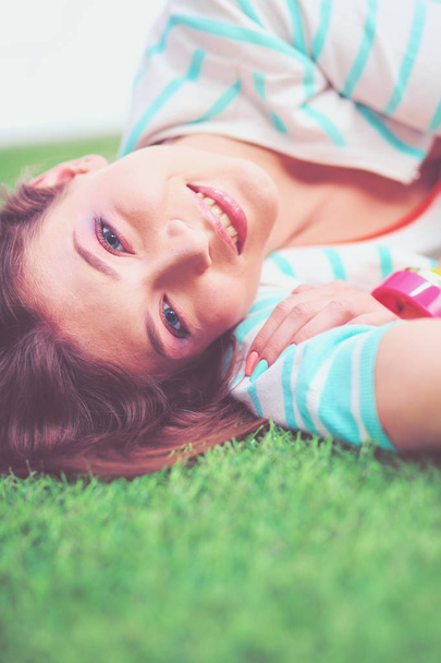 Beautiful young woman lying on the green grass - Fotoğraf, Görsel