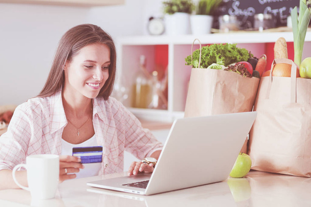 Smiling woman online shopping using tablet and credit card in kitchen . Smiling woman - Photo, Image