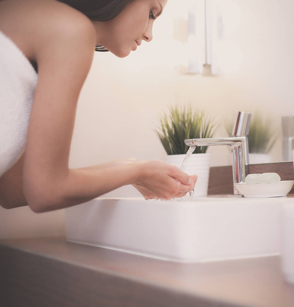 Mladá žena mytí obličeje s čistou vodou v koupelně - Fotografie, Obrázek
