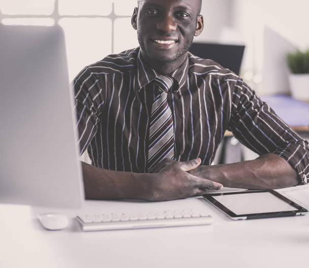 Handsome afro american businessman in classic suit is using a laptop and smiling while working in office - Foto, Bild