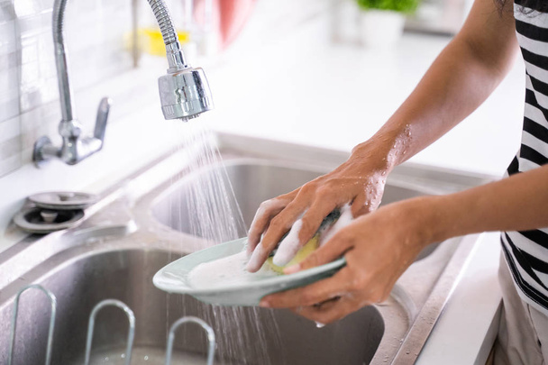 hand washing a plate on a sink - Фото, изображение