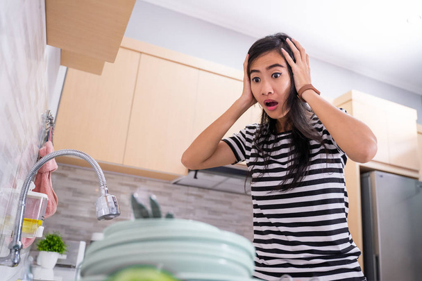 Lavaboda dishware bakarak şok kadın - Fotoğraf, Görsel