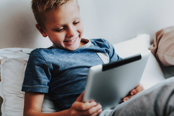 Happy boy sitting with digital tablet in hand - Valokuva, kuva
