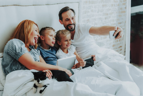 Family making funny selfie together in bed - Foto, imagen