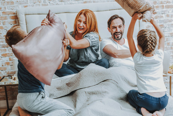 Happy family fighting by pillow together in bed - Foto, imagen