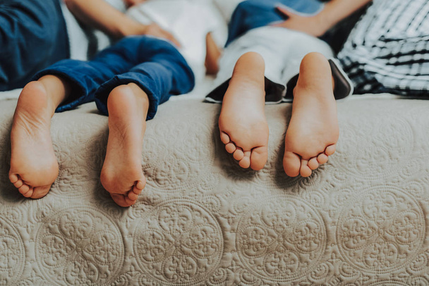 Close up of two pairs of kids feet in bed - Foto, imagen