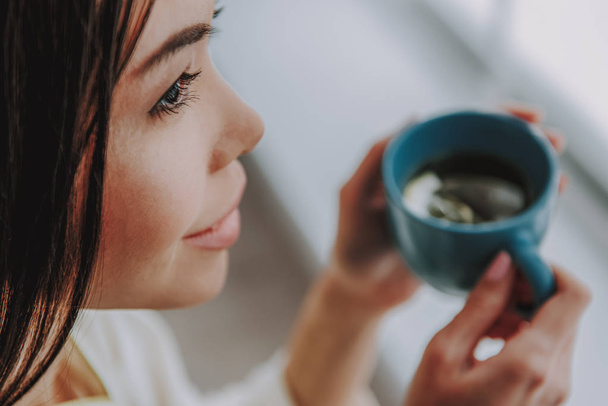 Profile of young lady tasting hot tea with lemon - Photo, Image