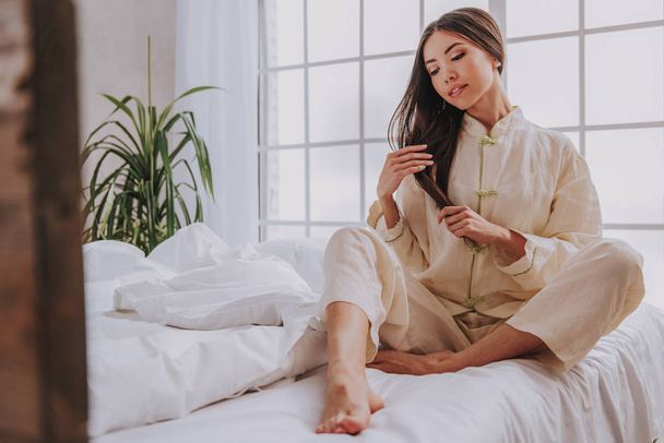 Thoughtful asian woman locating in light bedroom - Foto, imagen