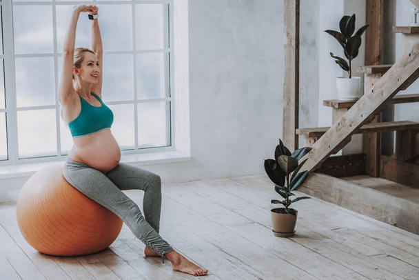 Happy pregnant female doing pilates at home - Фото, изображение