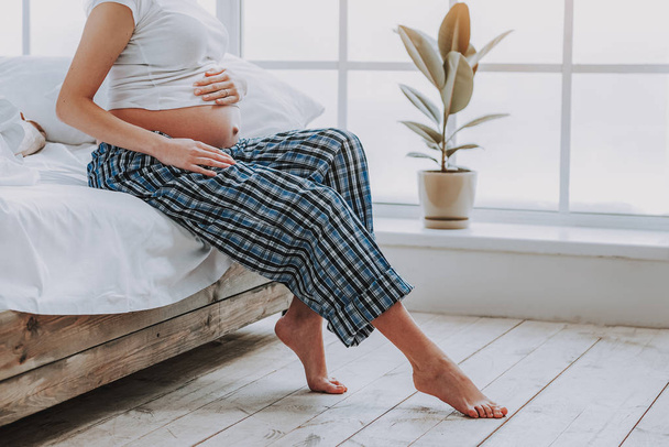 Expectant woman is sitting in cozy bedroom - Foto, Imagen