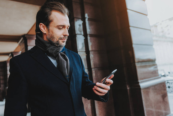Confident adult man is using smartphone outdoors - Photo, image