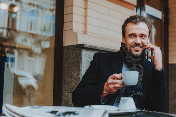 Joyful trendy man is communicating on smartphone in cafe - Photo, Image