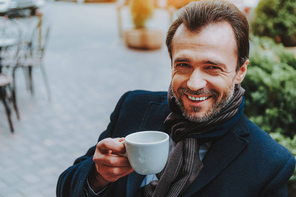 Happy man is having hot drink outside - Φωτογραφία, εικόνα