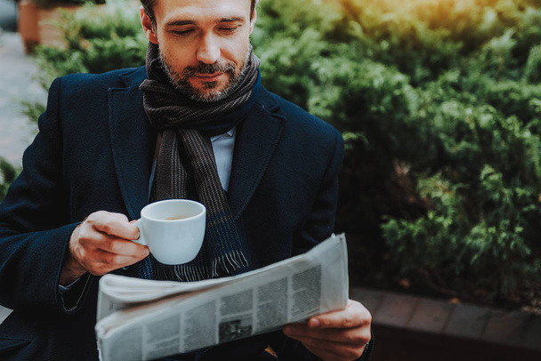 Elegant man is reading newspaper with cup of coffee outdoors - Foto, Bild