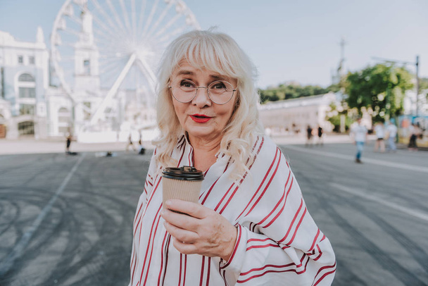 Beautiful mature woman is drinking coffee on square - Φωτογραφία, εικόνα