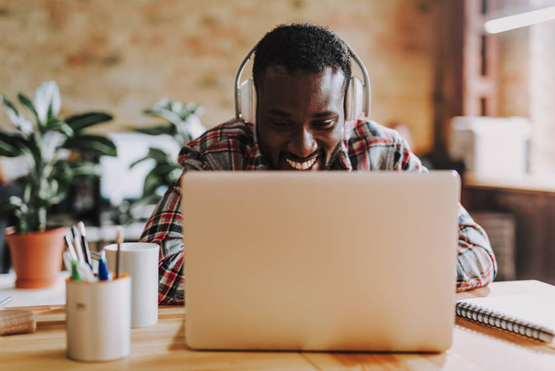 Positive young man wearing big headphones while using laptop - Foto, Bild