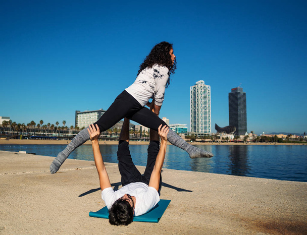 Hermosa pareja practicando acro yoga por la mañana
 - Foto, imagen