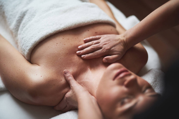 Young lady have low neck massage in spa salon - Fotó, kép