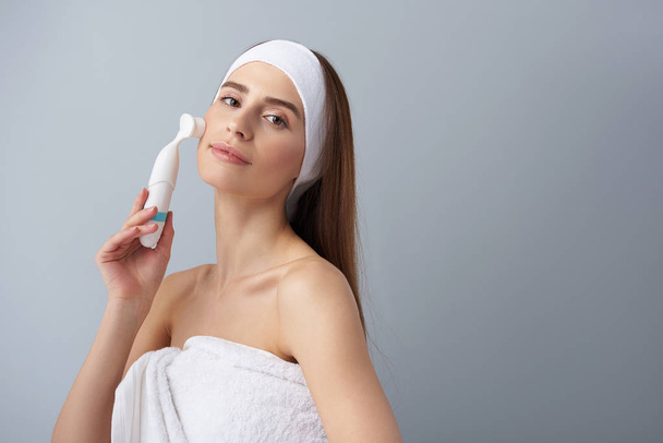 Beautiful young lady using pore cleansing brush after bath - Photo, image