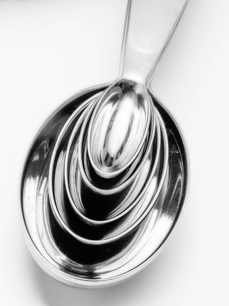 Shiny chrome kitchen measuring spoons nested together on white background. - Photo, Image
