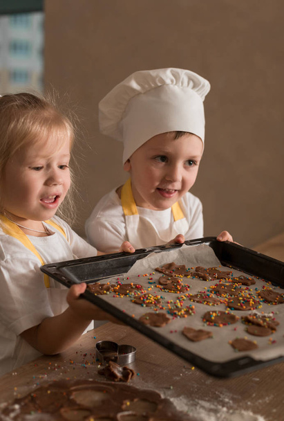 Happy Children in Caps and Apron Bake Cookies. Kitchen. Home Concept - Фото, изображение