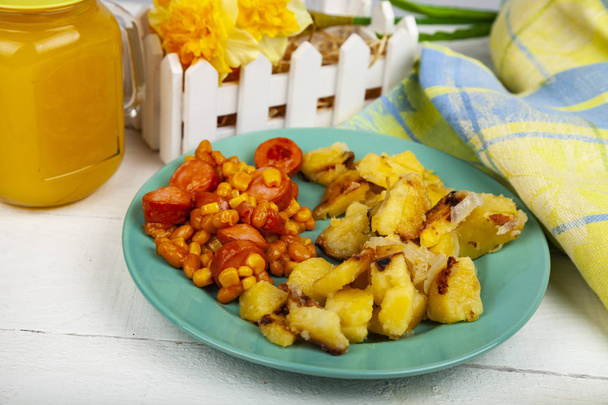 Жареный картофель с фасолью и сосисками на обеденном столе. Вкусная еда
. - Фото, изображение