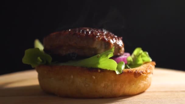 Concept of adding the ingredients to Cheese Burger, grilled meat, cheese, bacon, tomatoes, pickled cucumbers, red onion, sauce and then top bun falling - Footage, Video
